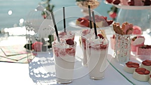 White table laden with sweet delicacies stands on shore of ocean.