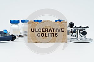 On a white table lie ampoules, a stethoscope and a cardboard with the inscription - ULCERATIVE COLITIS