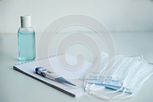 On a white table are a Notepad, medical masks, and antiseptic hand gel. to do list in case of illness