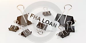 On a white table there are office clamps, in one clip there is paper with the inscription - FHA LOAN