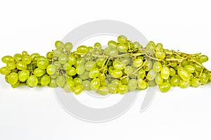 On a white table there is a very long bunch of green grapes