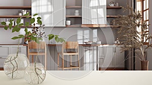 White table top or shelf with glass vase with hydroponic plant, ornament, root of plant in water, branch in vase, house plant,