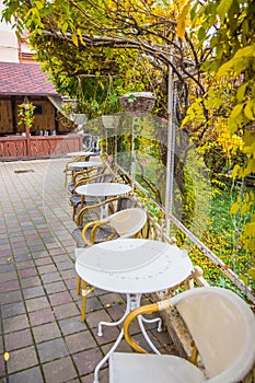 White tables in a cafe in autumn. Beautiful autumn in a cafe on the street. Street restaurant in autumn