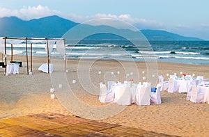 White tables served for supper on beach.