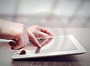 White tablet with a blank screen in the hands on table