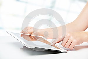 White tablet with a blank screen in the hands on table