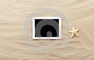 White tablet with blank screen on the sand