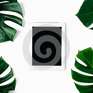 White tablet blank screen tropical leaves Monstera white background top view flat lay