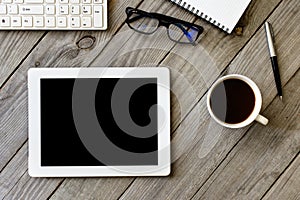 White tablet with blank screen on wooden table