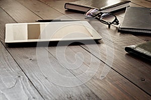 White tablet computer with office objects on office wooden table