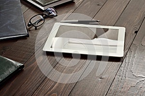 White tablet computer with office objects on office wooden table