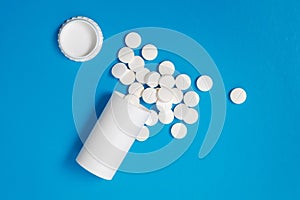 White tablets and bottle for tablets on blue background