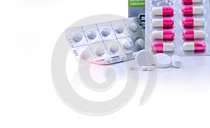 White tablets pills on white table and blurred pink-white capsule pills in blister pack. Pharmaceutical products. Pharmaceutical