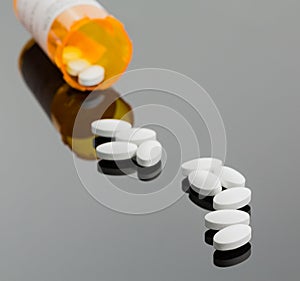 White tablets spilling from drug bottle