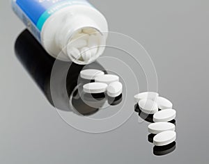 White tablets spilling from drug bottle