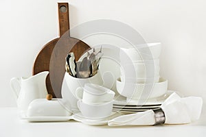 White tableware for serving. Crockery,dish, utensils and other different white stuff on white table-top. Kitchen still life as bac