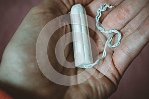 white tampon in hand of a woman, hygiene product for menstruation