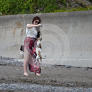 White and tan Jack Russell dog jumping for a ball held by a lady on a beach