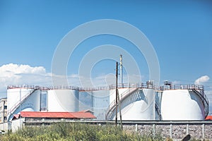 white tanks in tank farm with blue sky.