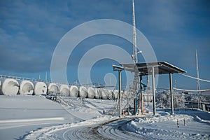 White tanks in tank farm with iron staircase in snow