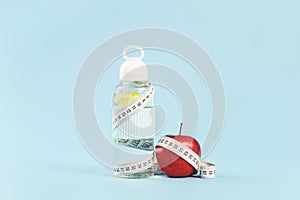 White tape measure around lemon water bottle and red apple