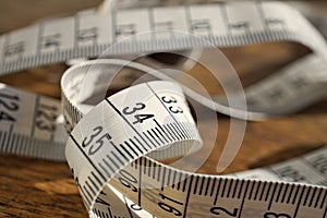 White tape measure tape measuring length in meters and centimeters on the woodensurface as symbol of tool used by tailor