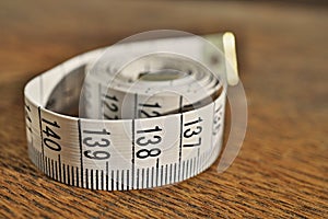 White tape measure tape measuring length in meters and centimeters on the woodensurface as symbol of tool used by tailor