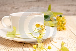 tea cup with linden flowers on wooden table