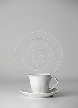 White tea cup and saucer with a pattern for drink on white background. Ceramic coffee cup or mug close up. Mockup