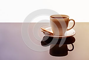 White tea mug with a saucer on a glossy table