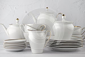 White tea set on a white background. Teapot, cream, sugar bowl, cups, saucers, plates on the table.