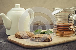 White teapot, cookies and half glass mint tea/white teapot, cookies and half glass mint tea on a wooden background