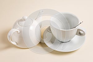 White teapot and an empty cup of tea spoon.