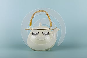 White teapot with eyes on a green background