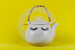 White teapot with eyes on a yellow background