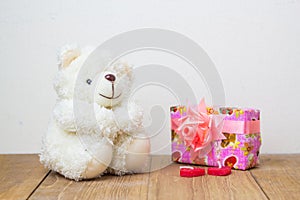 White teddy bear and gift box on wooden board