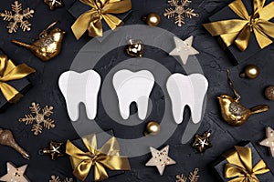 White teeth with gold decorations and gift boxes on black background. Dentist Merry Christmas and New Year concept