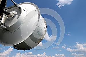 White telecommunication dish under cloudy sky