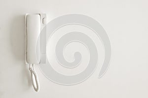 A white telephone hangs on a white wall