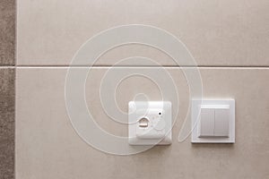 White temperature controller of a warm floor on a gray wall.