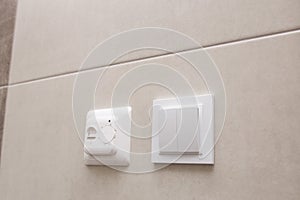 White temperature controller of a warm floor on a gray wall.