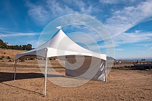 White tent in brown grass field under blue sky