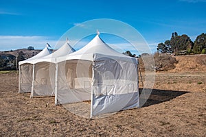 White tent in brown grass field under blue sky