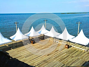 White tent on a wooden deck floating on the sea by the beach photo