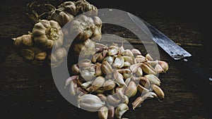 White Thai garlic and a kitchen knife placed on a black wooden background