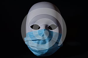 White theatrical mask wearing a blue medical protective mask, Artiste affected by pandemic, Corona virus protection, photo