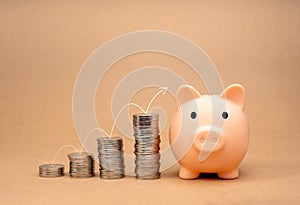 White thin line arrow jumping on coin stacks graph step to the cute pink piggy bank isolated on brown background. Saving money,