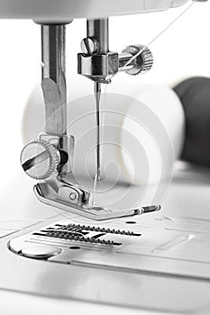 White thread through the needle eye.The side of the sewing machine