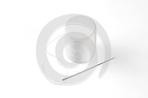 White thread through the needle eye with spool.