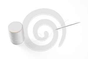 White thread through the needle eye with spool.
